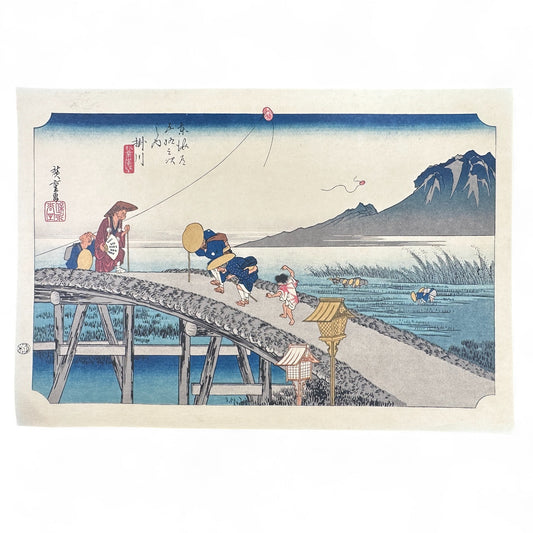 Utagawa Hiroshige woodblock print Kakegawa-juku from The Fifty-Three Stations of the Tōkaidō, travelers crossing bridge in strong wind, traditional Japanese ukiyo-e reproduction.