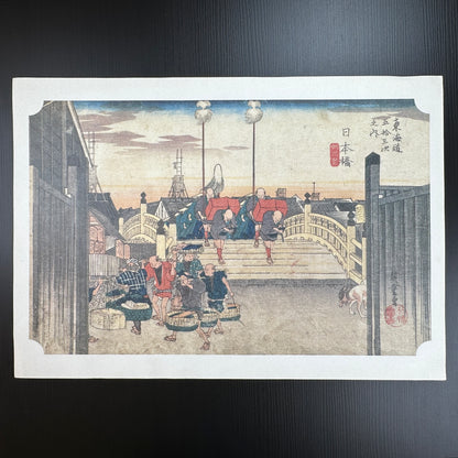Utagawa Hiroshige woodblock print Nihonbashi Morning Scene from The Fifty-Three Stations of the Tōkaidō, travelers on bridge at sunrise, Japanese ukiyo-e reproduction.